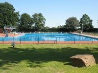 Freibad Mettingen Das Freibad Mettingen. Außenanlage mit großer Rasenfläche und Bäumen im Hintergrund